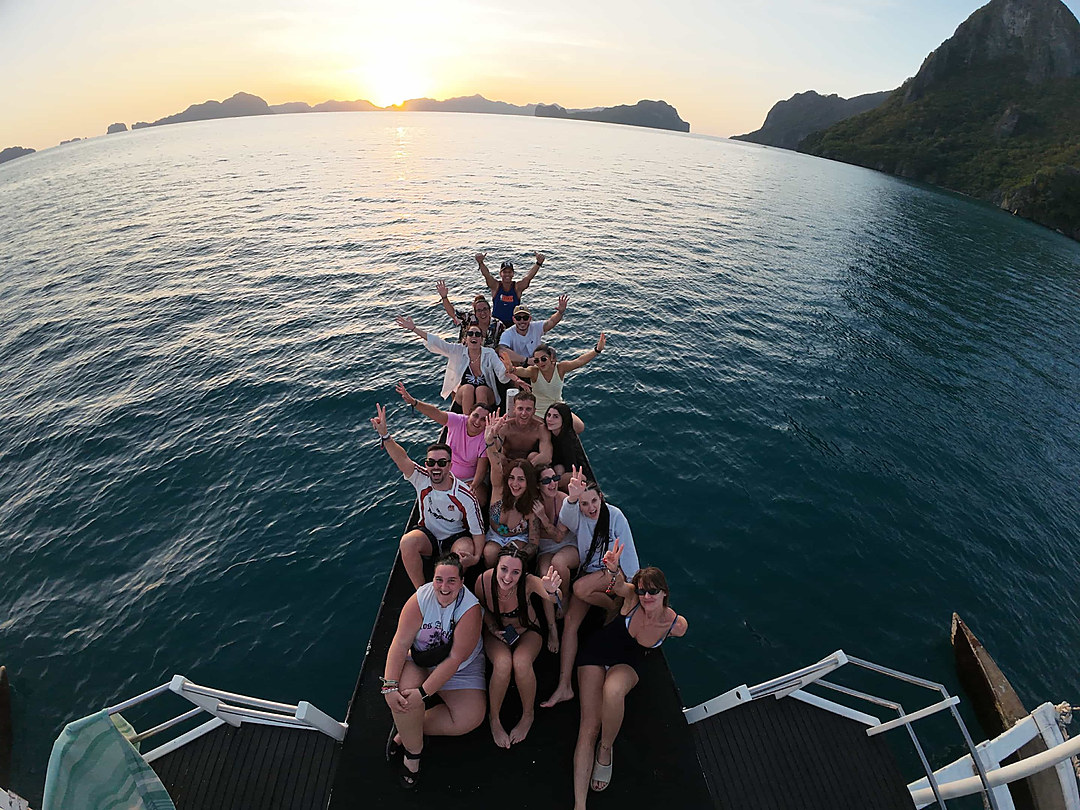 Kraken guests aboard a two-level boat at sunset in El Nido